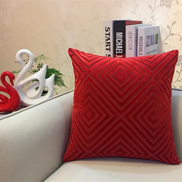 Red textured pillow on a couch with decorative items in the background