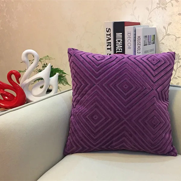 Purple textured pillow on a couch with decorative items in the background