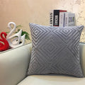 Gray textured pillow on a light-colored sofa with decorative items in the background.