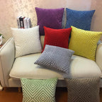 Colorful textured pillows on a beige sofa against a floral wallpaper background