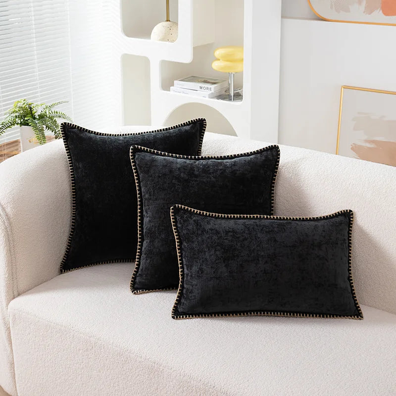 Three black decorative pillows on a white couch in a living room setting.