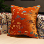 Decorative orange pillow with intricate patterns on a couch.