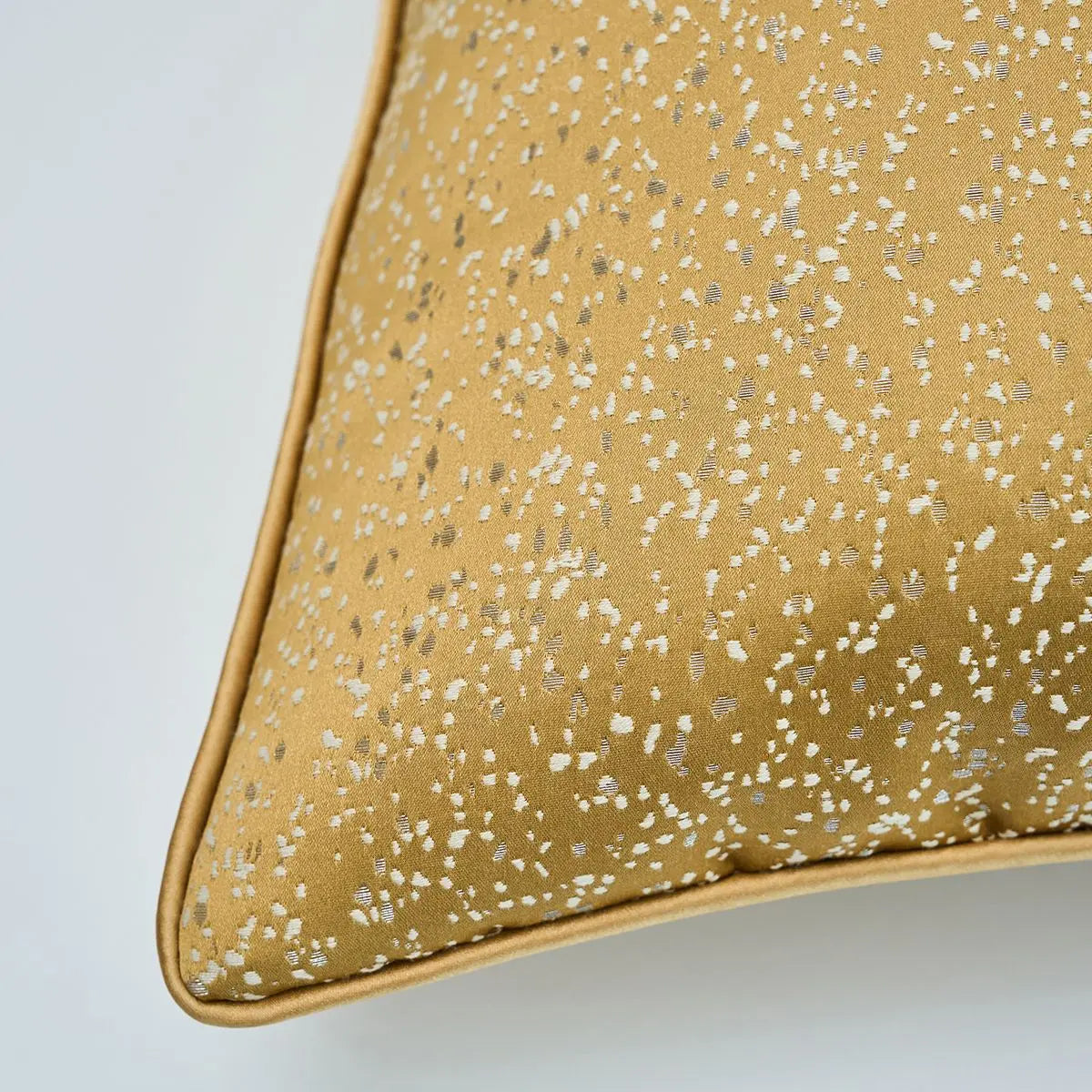 Gold pillow with a subtle pattern on a light gray background