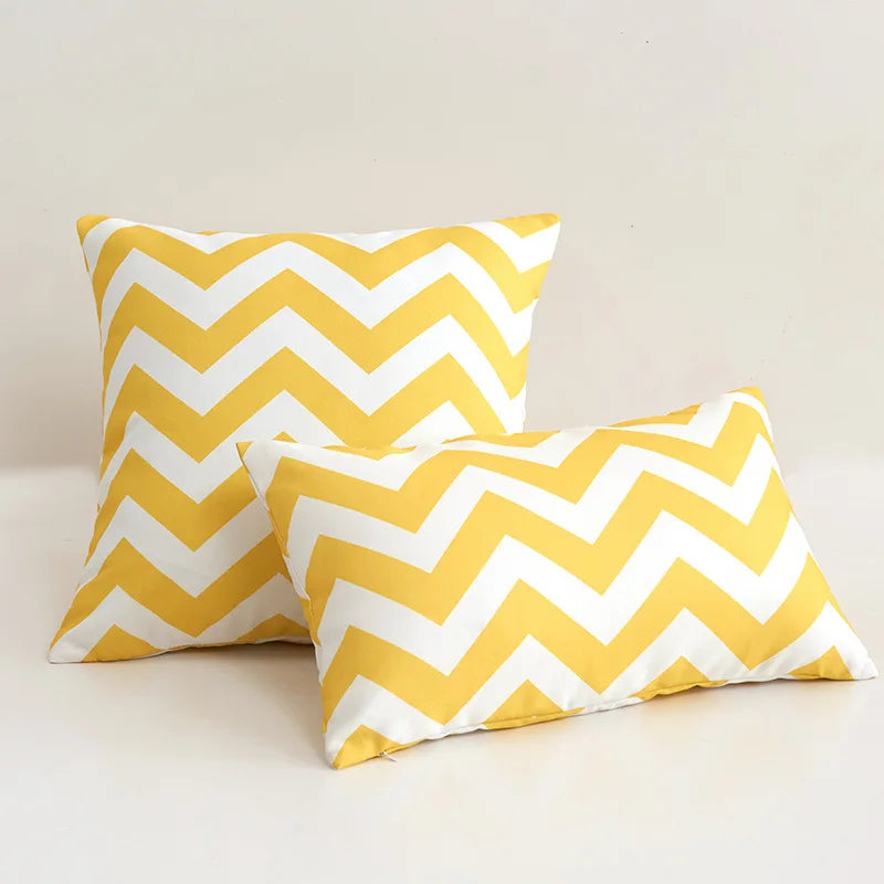 Two yellow and white chevron patterned pillows on a light background