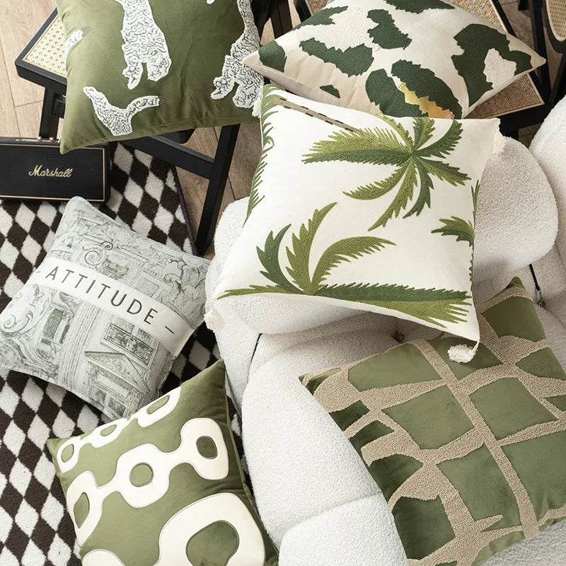 Collection of green and white patterned cushions on a sofa.