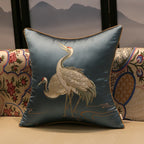 Decorative pillow with embroidered crane design on a patterned background