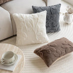 Decorative pillows with leaf pattern on a sofa in a living room setting.