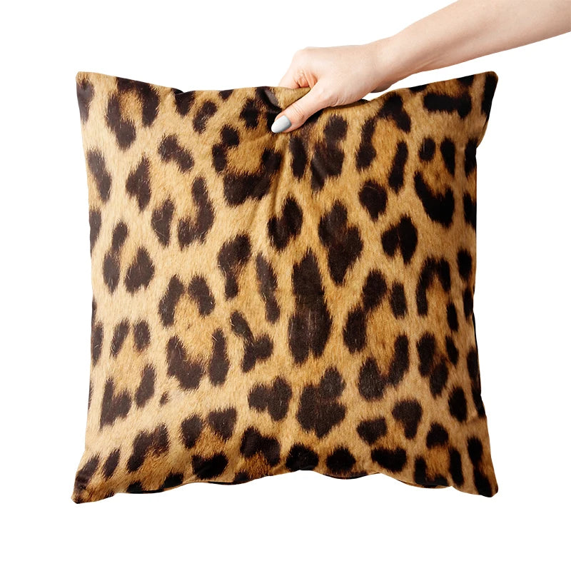 Leopard print pillow held by a hand on a white background