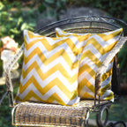 Yellow and white chevron patterned pillow on a wicker chair outdoors.