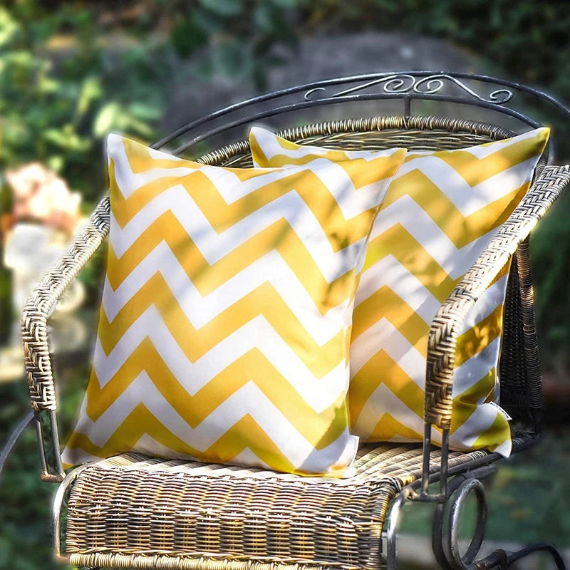 Yellow and white chevron patterned pillow on a wicker chair outdoors.