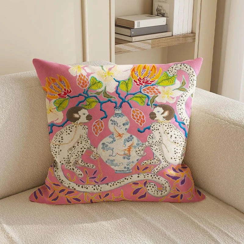 Decorative pillow with leopards and floral design on a beige couch.