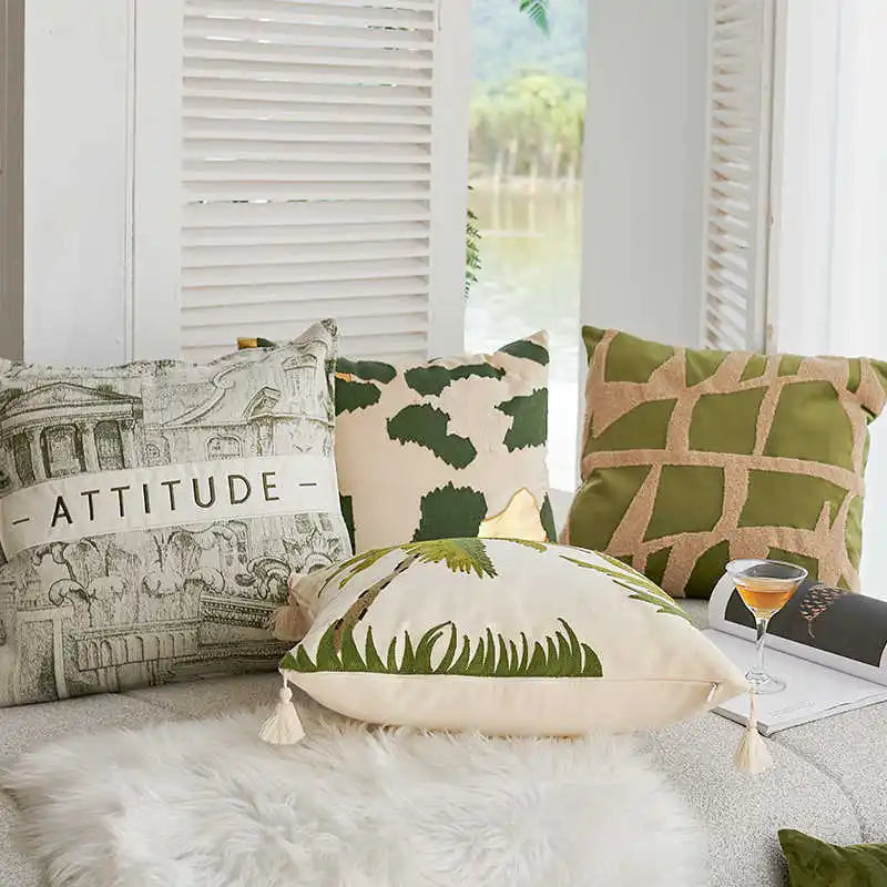 Decorative pillows with various patterns and text on a textured surface.