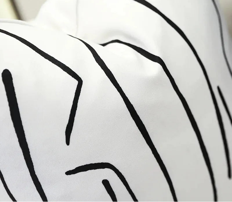 White cushion with black abstract patterns on a neutral background