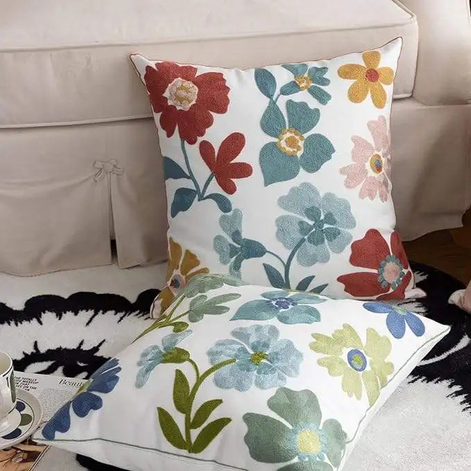 Floral patterned pillows on a couch with a coffee cup and magazine.