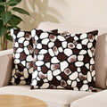 Two patterned pillows on a beige sofa with a plant in the background