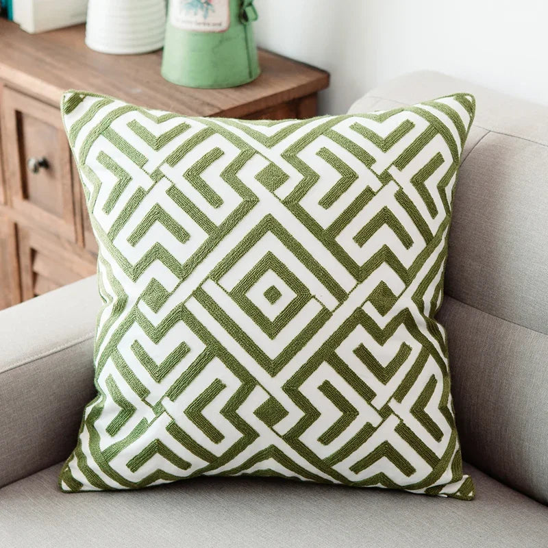 Green and white geometric patterned pillow on a gray sofa