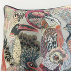 Decorative pillow with intricate bird and floral pattern on a neutral background