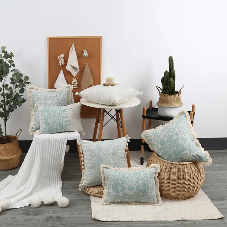Decorative pillows on a chair and floor with a plant and bulletin board in the background.
