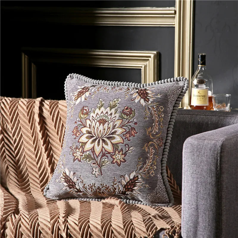 Decorative pillow with floral pattern on a couch next to a bottle and glass.