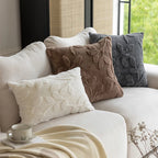 Decorative pillows on a sofa with a cup and blanket in a cozy living room.
