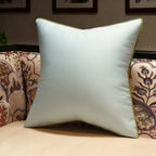 White pillow with gold trim on a patterned sofa