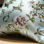 Embroidered pillow with floral and bird patterns on a light blue background