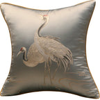 Decorative pillow with embroidered cranes on a light background