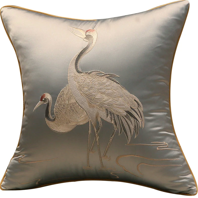 Decorative pillow with embroidered cranes on a light background