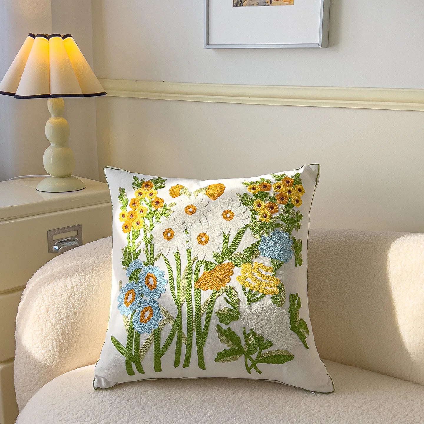 Decorative pillow with floral embroidery on a couch next to a lamp.