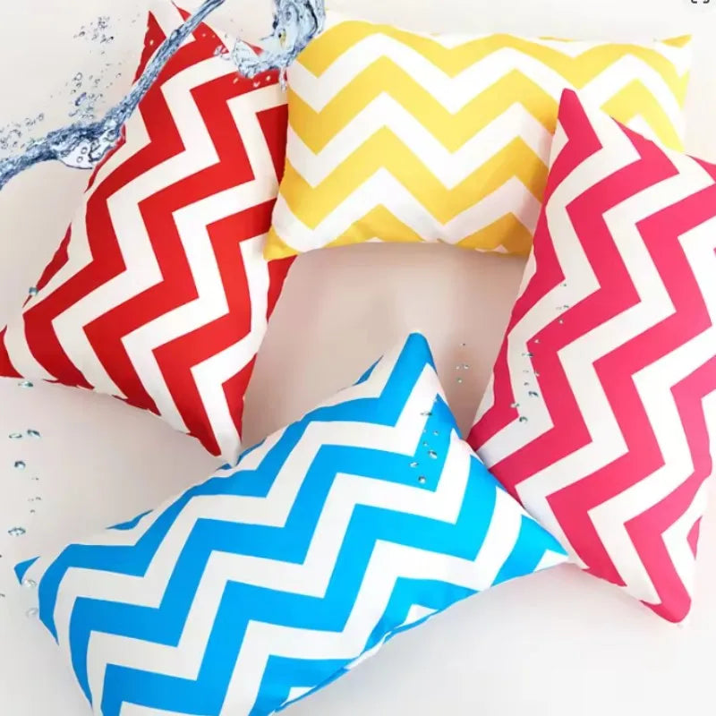 Four colorful chevron-patterned pillows on a white surface.