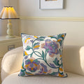 Decorative pillow with floral pattern on a couch next to a lamp.