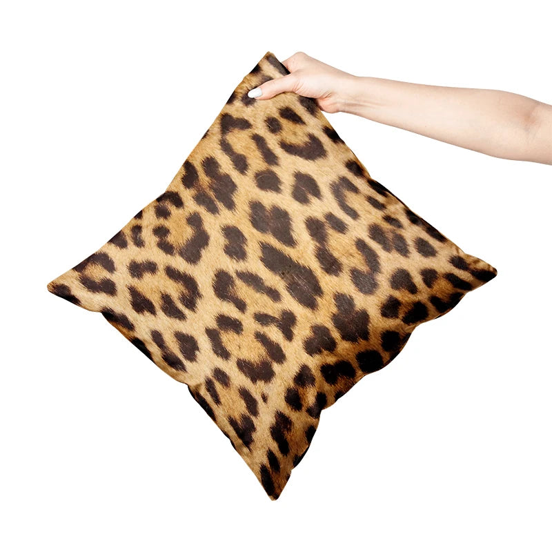 Leopard print pillow held by a hand on a white background