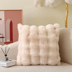 Fluffy beige pillow on a sofa with a decorative background