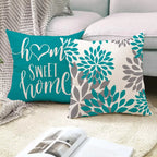 Two decorative pillows on a couch with one reading 'home sweet home' and the other with floral patterns.
