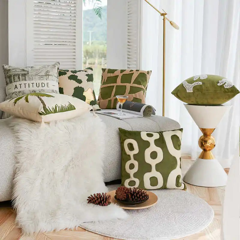 Living room with a gray sofa adorned with green and patterned cushions, a white lamp, and decorative items.