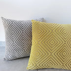 Two patterned pillows, one gray and one yellow, on a light gray surface.