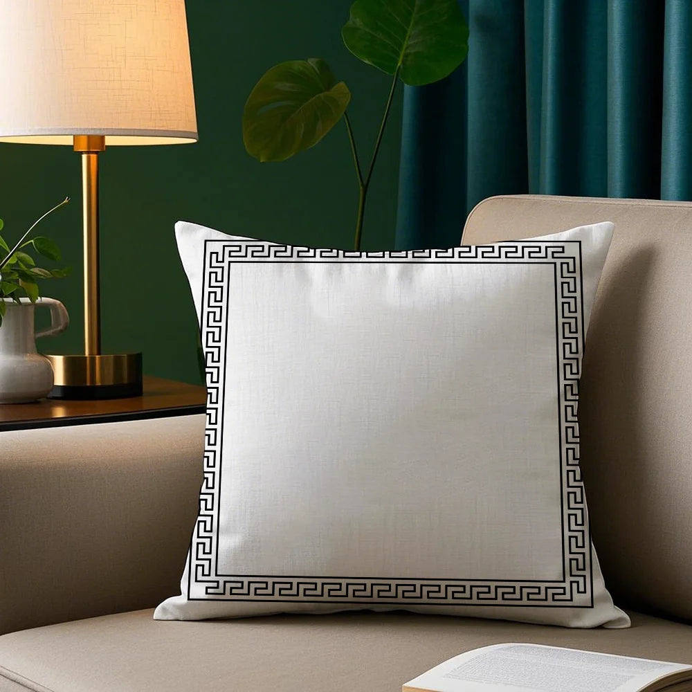 White pillow with decorative black border on a beige sofa against a green wall with a lamp and plant.