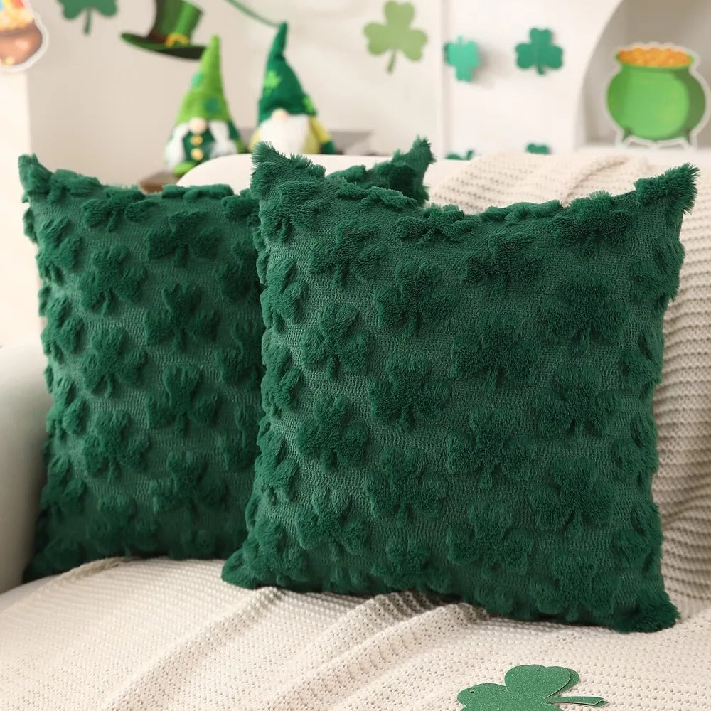 Two green textured pillows on a couch with festive decorations in the background.