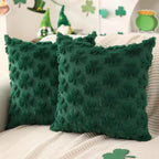 Two green textured pillows on a couch with festive decorations in the background.