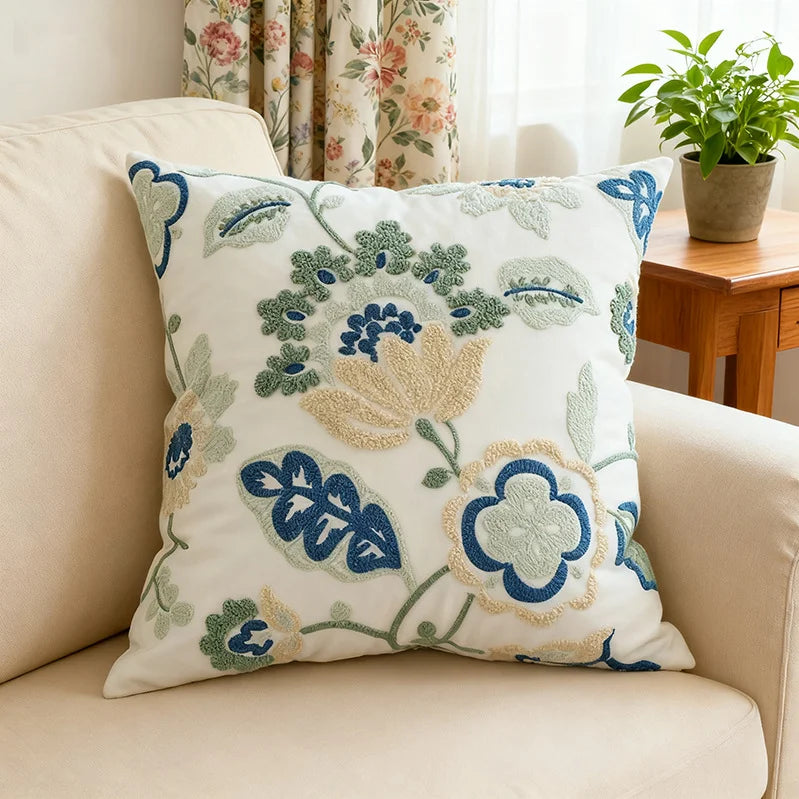 Decorative pillow with floral patterns on a beige sofa in a living room setting.