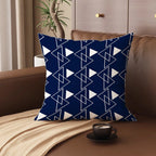 Blue and white geometric patterned pillow on a brown couch with a cup of coffee.