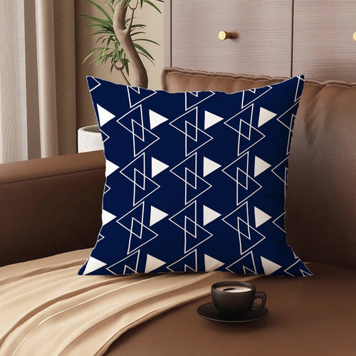 Blue and white geometric patterned pillow on a brown couch with a cup of coffee.