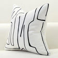 Decorative pillow with black abstract line design on a white background