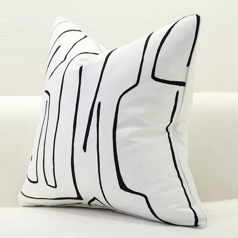 Decorative pillow with black abstract line design on a white background