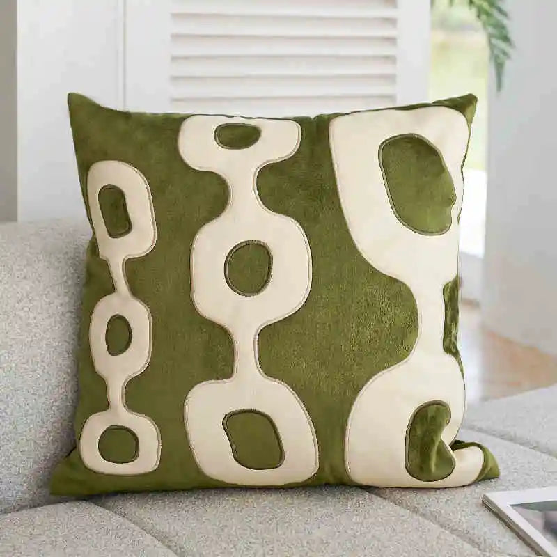 Green pillow with abstract white patterns on a gray couch.