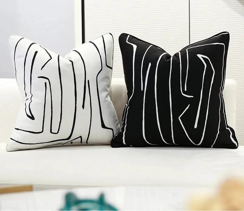 Two black and white abstract patterned pillows on a couch.