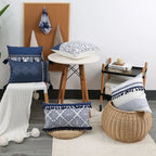 Decorative pillows with blue and white patterns on a chair and stool in a room setting.