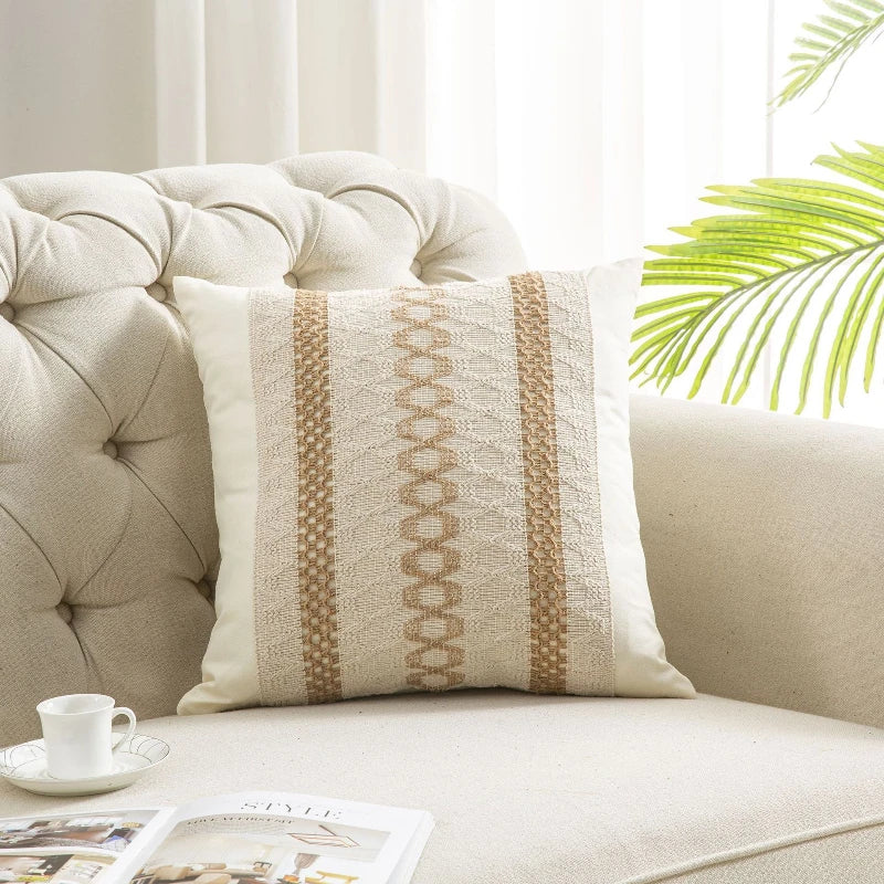 Decorative pillow with striped pattern on a beige sofa with a cup and magazine.