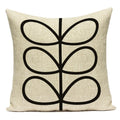 Beige pillow with black abstract leaf design on a white background