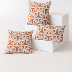 Three orange and white patterned pillows on a white surface